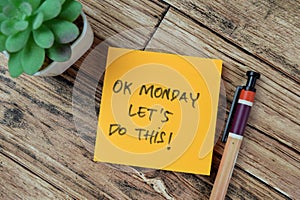 Concept of OK Monday Let's Do This! write on sticky notes isolated on Wooden Table