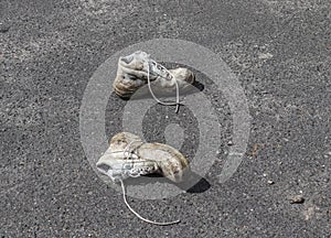 Concept of old shoes left on an ashpalt road with copy space for text