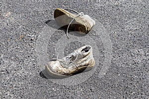 Concept of old shoes left on an ashpalt road with copy space for text