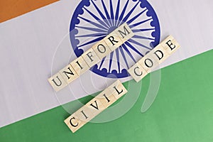 Concept of One law for all called Uniform Civil code or UCC in Indian constitution in wooden block letters on Indian flag