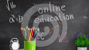 The concept of online learning. A spinning glass with colored pencils on the background of a chalkboard with the text `Online educ