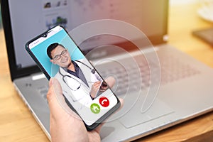 Concept of online medical healthcare, shows smartphone app with Asian male doctor smiling, telehealth, telemedicine video call