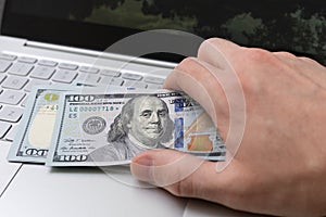 The concept of online payment or transfer. Hand with money near the laptop