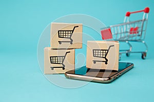 Concept of online Shopping. Boxes and shopping bag above smartphone isolated on blue background