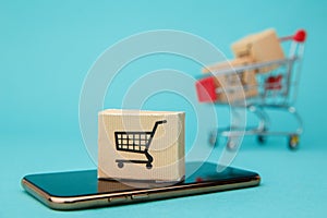 Concept of online Shopping. Boxes and shopping bag above smartphone isolated on blue background