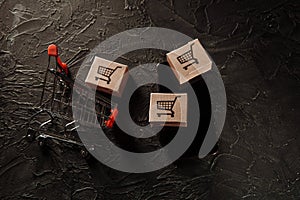 Concept of online shopping. Boxes, shopping cart and smartphone on a grey background