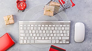 Concept online shopping buying presents. Red credit card, keyborad and christmas presents on grey