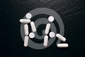 The concept of oral sex in the form of people from pills on a rough black background