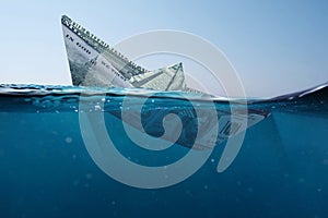 Concept paper dollar boat sinking in the sea with a view underwater. Finance and crisis, a creative idea. Falling exchange rates.