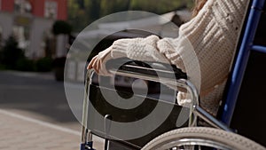 Concept of paralysis, disability, help and support. Man put his hand on hand of disabled woman on wheelchair, close up