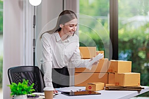 Concept of parcel delivery and selling online,Retailer Using a calculator to calculate sales for the day on an online store for