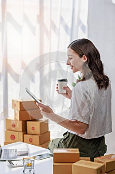 Concept of parcel delivery and selling online,Retailer Using computer tablet to check sales for the day on an online store while