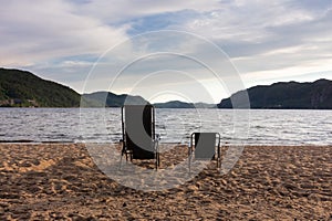 Concept parent chair and child chair on sand beach sunset with pine sea, pain trees and mauntain on background