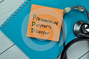 Concept of PDD - Premenstrual Dysphoric Disorder write on sticky notes isolated on Wooden Table