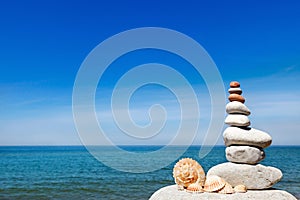 Concept of peace and harmony. A pyramid of white stones and shells on background of summer sea