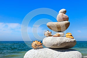 Concept of peace and harmony. A pyramid of white stones and shells on background of summer sea