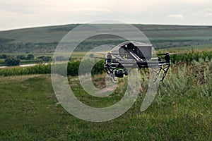The concept people and agriculture - black drone with digital camera flying in sky over field on sunset.
