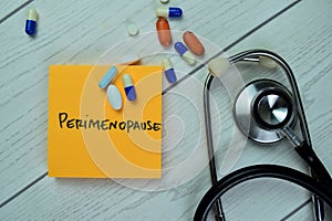 Concept of Perimenopause write on sticky notes with stethoscope isolated on Wooden Table photo