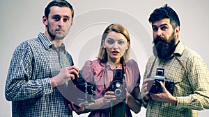 Concept of a photo case. Two guys and a girl in the process of creating a photo. Photographers are studying old cameras.