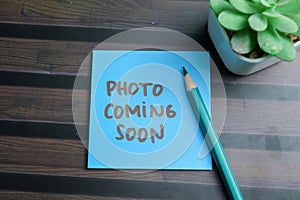 Concept of Photo Coming Soon write on sticky notes isolated on Wooden Table