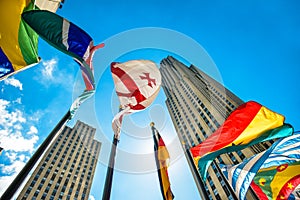 Concept photo of global international corporate business. Skyscrapers and international flags against blue sky at sunny day