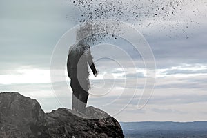 A concept photo of a hooded figure standing on a hill as his head disintegrates into the air.