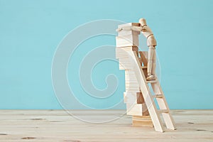 concept photo of obstacles overcoming, wooden dummy looking at a barrier and thinking about solution.