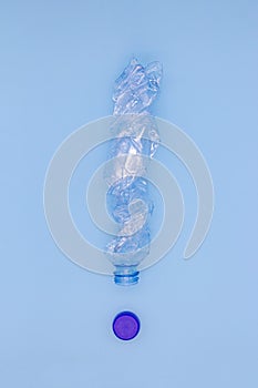 Concept of plastic pollution of nature, a plastic bottle in the shape of an exclamation mark on a blue background
