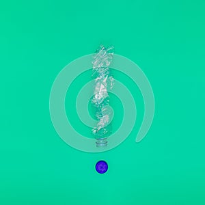 Concept of plastic pollution of nature, a plastic bottle in the shape of an exclamation mark on a green background