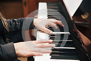 Concept of playing piano lessons. The young girl plays at home on a piano and studies new musical works