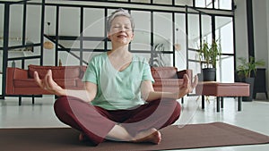 Concept of a pleasant and useful pastime in old age. Old woman make yoga exercise at home. Mature woman have meditation