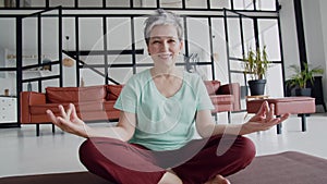 Concept of a pleasant and useful pastime in old age. Old woman make yoga exercise at home. Mature woman have meditation