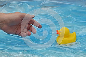 Concept Pollution Plastic In Sea with Yellow Rubber Duck and Man Hand
