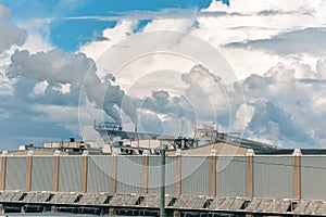 Concept of pollution. The smoke from the chimneys, mixes with the clouds in a blue sky. Canada