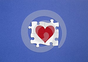 Concept of polyamory. copy space. white puzzle pieces with red heart on blue background
