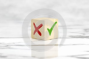 Concept of positive or negative decision making or choice of approval or rejection. Tick mark and cross mark x on wooden cube.