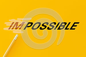 Concept of positive thinking, word impossible erased with an eraser and changed to possible, yellow background