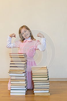 Concept The power of knowledge. A girl with a pile of books shows her strength. Education concept. copy space. vertical photo