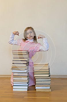 Concept The power of knowledge. A girl with a pile of books shows her strength. Education concept. copy space. vertical photo