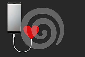 Concept of the power of love, on dark background  isolated Mobile smart phone with blank screen that is charging from red heart