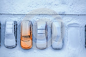 Concept of pre-heating system at winter night. Line from several cold cars with one warmed photo