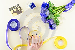 Concept of preparation for the holiday or wedding. Blue flowers, card, ring, yellow and blue ribbon on light background. Top view