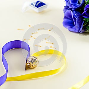 Concept of preparation for the holiday or wedding. Blue flowers, ring and heard made of ribbons on light background. Top view, fl