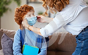 Concept of preventing a coronavirus covid-19 and viral infections. Mother puts on medical mask for little son before leaving home