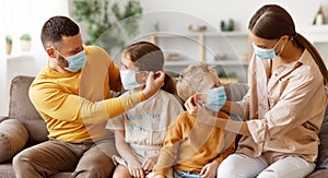 Concept of prevention of coronavirus infection. happy family: caring parents put protective medical masks on their children  in