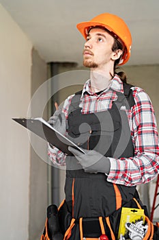 Concept of profession, construction and building. Young male worker or builder with clipboard