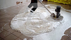 Concept of professional carpet cleaning. Worker cleans dirty carpet with foam after cleaning using scrubber machine.