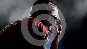 Concept of professional team sport. Silhouette of determined American football player in bright stadium light preparing