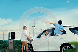 Concept of progressive happy family at wind farm with electric vehicle.