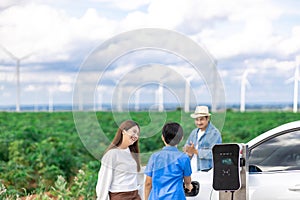 Concept of progressive happy family at wind farm with electric vehicle.